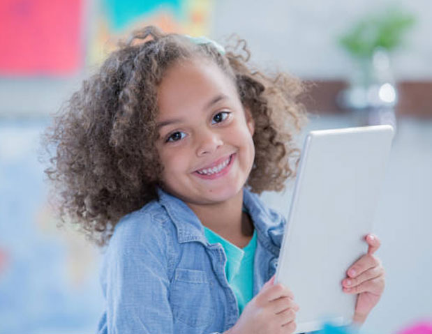 smiling toddler holding a tablet